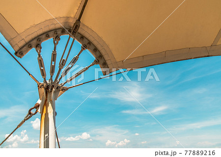 Connection points of tension membrane roof. Turnbuckle wire rope tension for tension membrane roof on a blue sky background. Connection points of tension membrane roof. Turnbuckle wire rope tension for tension membrane roof on a blue sky background. 77889216
