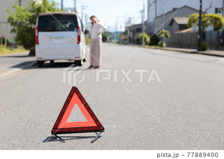 車が故障して三角停止表示版を置く女性 車が故障して三角停止表示版を置く女性 77889400