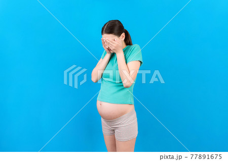 Beautiful young pregnant woman feeling head ache on colored background isolated. Stressed pregnant woman or mother problems 77891675