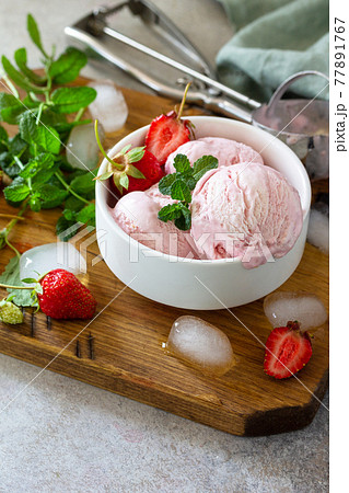Homemade Organic Strawberry Ice Cream. Strawberry ice cream balls with mint leafon a light stone or slate table. Copy space. 77891767