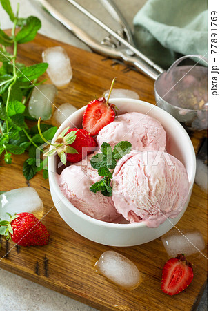 Homemade Organic Strawberry Ice Cream. Strawberry ice cream balls with mint leafon a light stone or slate table. 77891769