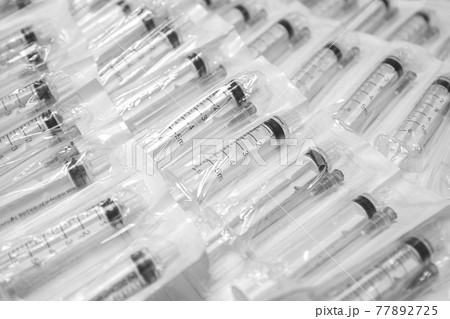 Medical syringes in a package. A bunch of unused, packaged syringes.Many new syringes lie strewn on a flat surface. 77892725