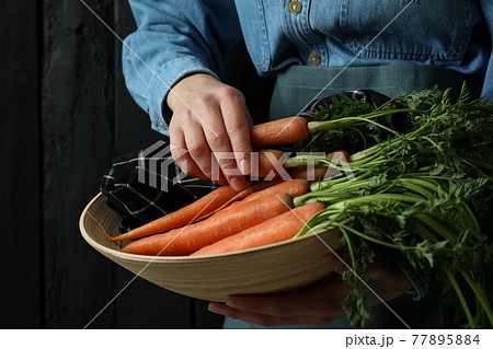 Woman hold bowl with carrot against dark wooden background Woman hold bowl with carrot against dark wooden background 77895884