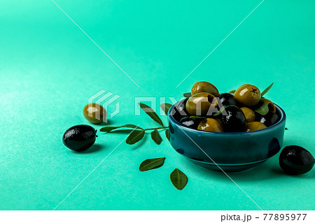 Bowl of olives and leaves on mint background 77895977
