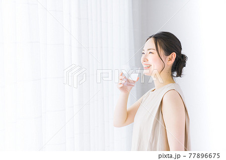 ミネラルウォーターを持つ若い女性 77896675