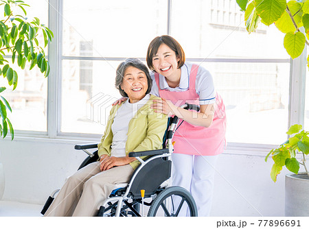 車いすを押す若い介護士 77896691