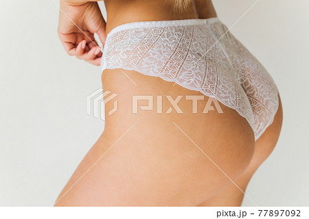 Cropped photo of an attractive young woman s hips wearing in black lingerie with stockings, laces. Sideways. Erotic ladies fashion concept. 77897092