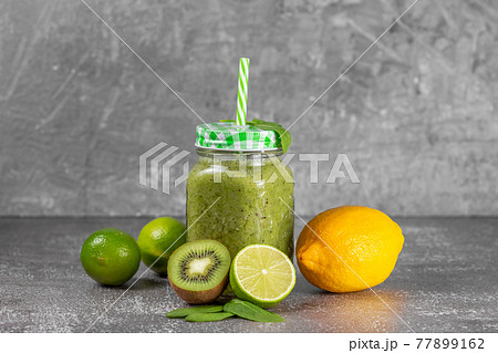 Freshly made kiwi lime and spinach smoothie on a gray concrete background. Freshly made kiwi lime and spinach smoothie on a gray concrete background. 77899162