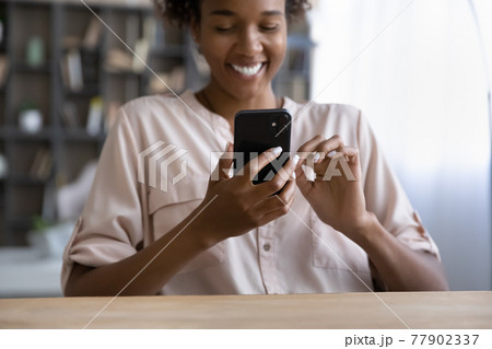 Smiling young african woman using smartphone indoors. 77902337