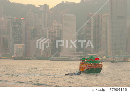 Sunset skyline of Hong Kong with traditional cruise sailboat at Victoria harbor 30 Dec 2006 77904156