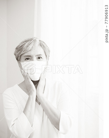 Senior asian woman wearing surgical mask during coronavirus and flu outbreak. Virus and illness protection, home quarantine. COVID-19. Taking on or taking off masks. 77906913