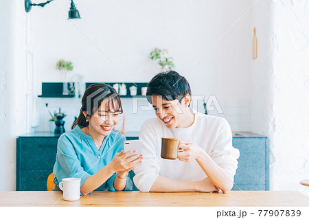 一緒にスマホを見る若い夫婦 カップル 77907839