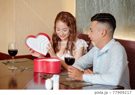 Woman opening romantic present Woman opening romantic present 77909217