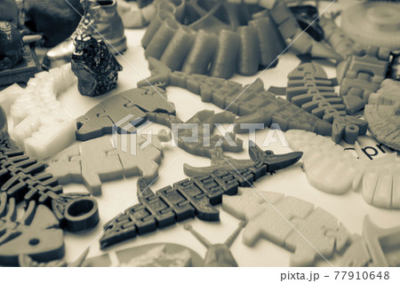 Many bright multi-colored objects printed on 3d printer lie on flat surface 77910648