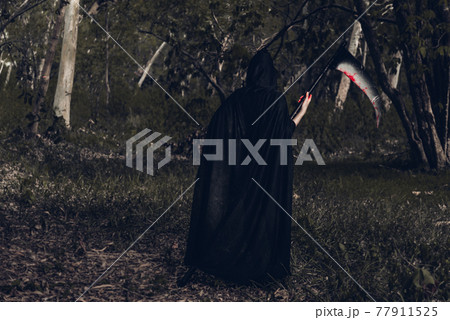 Back woman horror ghost holding reaper in forest 77911525