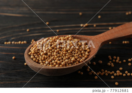 Wood spoon with mustard seeds on wooden background 77912681