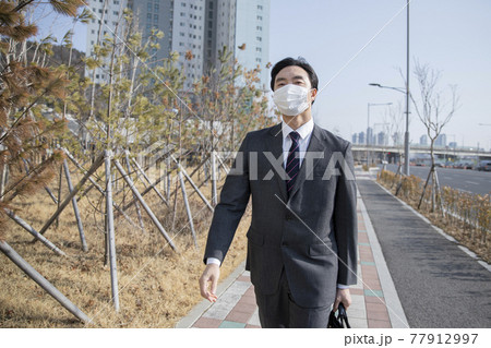 Asian business man in suit wearing mask on way to work by foot 77912997