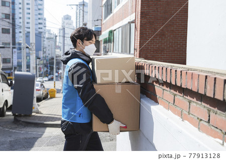 Asian Korean delivery man, working while wearing mask due to covid concept Asian Korean delivery man, working while wearing mask due to covid concept 77913128