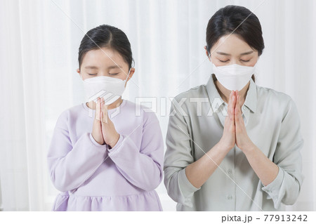 praying Asian mom and daughter wearing mask, covid virus safety concept praying Asian mom and daughter wearing mask, covid virus safety concept 77913242