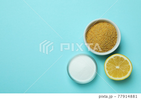 Bowls with mustard powder and acid powder, and half of lemon on blue background Bowls with mustard powder and acid powder, and half of lemon on blue background 77914881