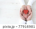 男女の手に包まれたハートのオブジェ 77916981