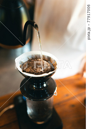 Drip coffee, barista pouring water on coffee ground with filter 77917006