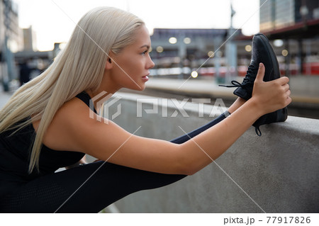 Close-up of a young woman stretching her muscles after running 77917826
