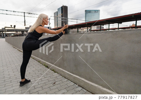 A young woman stretching her muscles after running 77917827