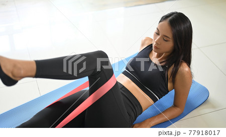 A beautiful woman is doing exercise in a comfortable living room. 77918017