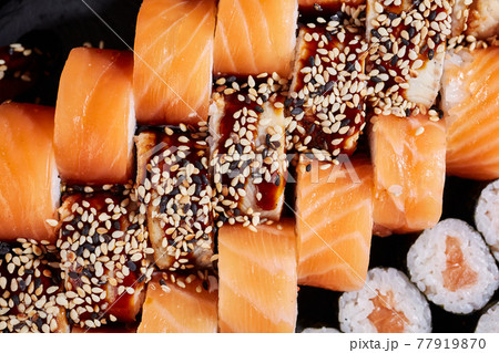 Top view of Philadelphia sushi rolls and sashimi rolls with sauce and sesame seeds. 77919870