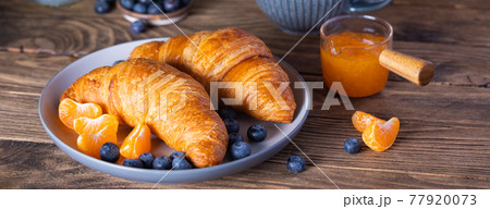 Breakfast with croissants, fresh blueberries, tangerines and jam on the wooden background 77920073