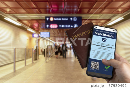 Traveler holds vaccine passport certificate to show COVID 19 vaccination status 77920492