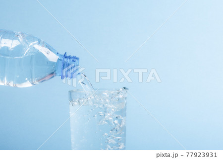 Pouring water from a plastic bottle into a glass beaker. 77923931