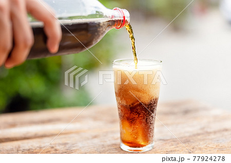 Bottle Pouring Drink In Glass On wooden table in garden 77924278
