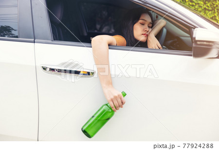 woman drinking from a beer bottle while driving car, a concept of driving intoxicated 77924288