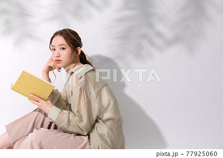 屋外で読書をする若い女性 77925060