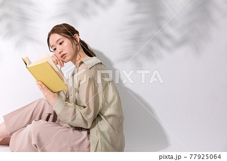 屋外で読書をする若い女性 77925064