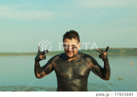 therapeutic mud for the body. mud baths on the lake. a man are smeared with clay therapeutic mud for the body. mud baths on the lake. a man are smeared with clay 77925685