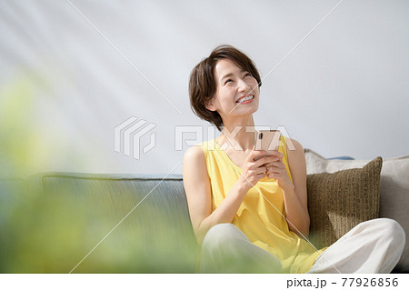 ミドル女性 スマホ 笑顔 ソファー ミドル女性 スマホ 笑顔 ソファー 77926856