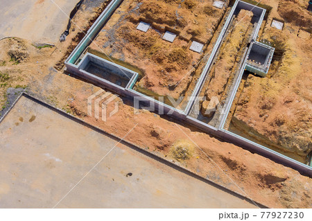 Building site of trenches dug in ground and filled with cement as foundation for future house 77927230