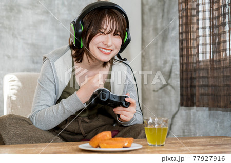 部屋でネットゲーム（オンラインゲーム）をプレイする女性 77927916