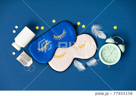 Blue and pink sleeping masks, pills and herbal tea on blue background, concept of rest, quality of sleep, good night, insomnia, relaxation Blue and pink sleeping masks, pills and herbal tea on blue background, concept of rest, quality of sleep, good night, insomnia, relaxation 77933156