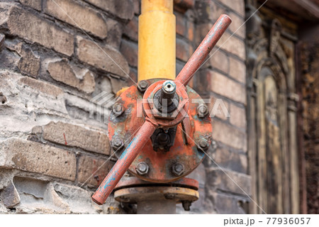 dirty gas valve with a yellow pipe on the wall of an old house dirty gas valve with a yellow pipe on the wall of an old house 77936057
