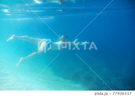 Woman swimming underwater Woman swimming underwater 77936317