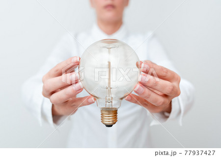 Lady Holding Lamp With Formal Outfit Presenting New Ideas For Project, Business Woman Showing Bulb With Two Hands Exhibiting New Technologies, Lightbulb Presenting Another Openion 77937427