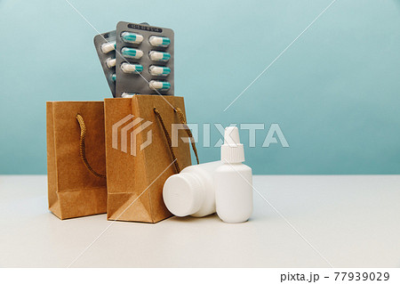 Online shopping theme. Bags with medical white containers and pills on blue background 77939029