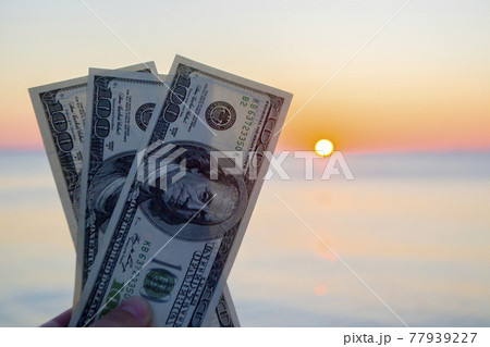 Three hundred dollar bills on background of sea surface at sunset dawn Three hundred dollar bills on background of sea surface at sunset dawn 77939227
