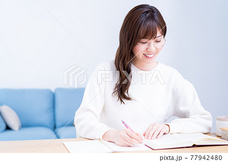 リビングで学習する眼鏡の若い女性 リビングで学習する眼鏡の若い女性 77942480