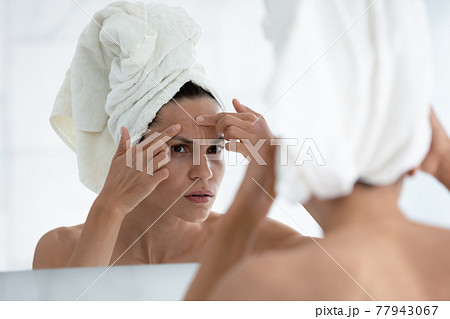 Serious millennial girl concerned about facial skin problem Serious millennial girl concerned about facial skin problem 77943067