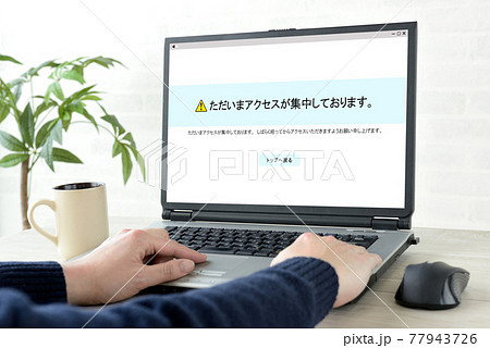 アクセス集中の画面が映し出されたパソコンと男性の手元 77943726